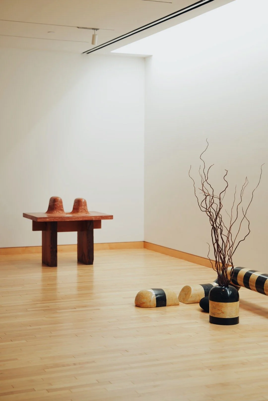 Minimalist art installation in gallery with wooden bench, two ceramic cups in Isamu Noguchi Garden Museum in Long Island City. Museum, cultural space/interior photography.