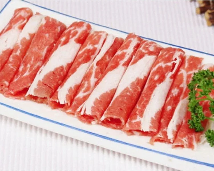Sliced beef or pork on a white rectangular platter garnished with parsley
