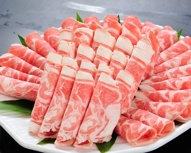 Thinly sliced marbled beef arranged in a circular pattern on a white platter with green garnish.