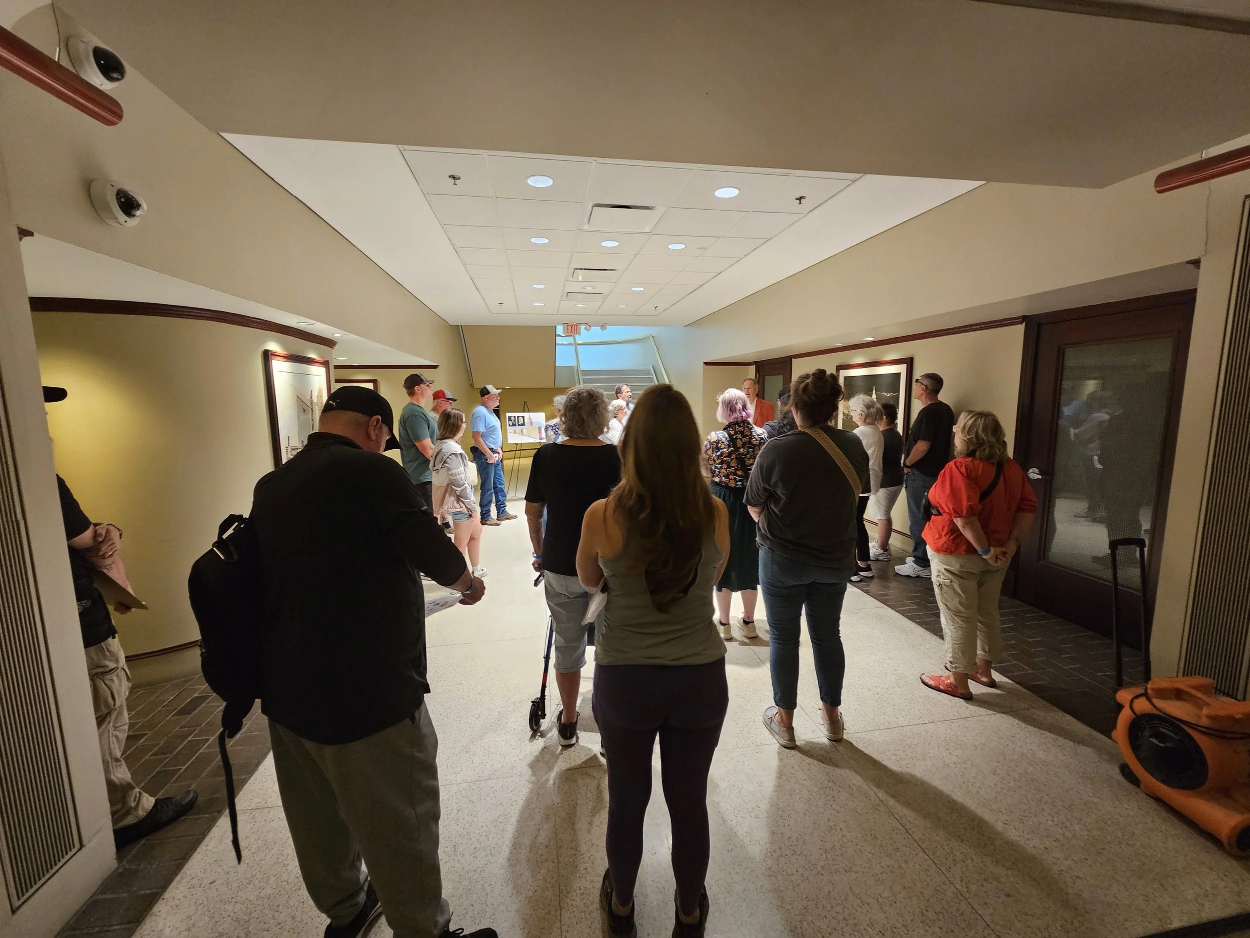 People waiting in line inside a building near an art display.