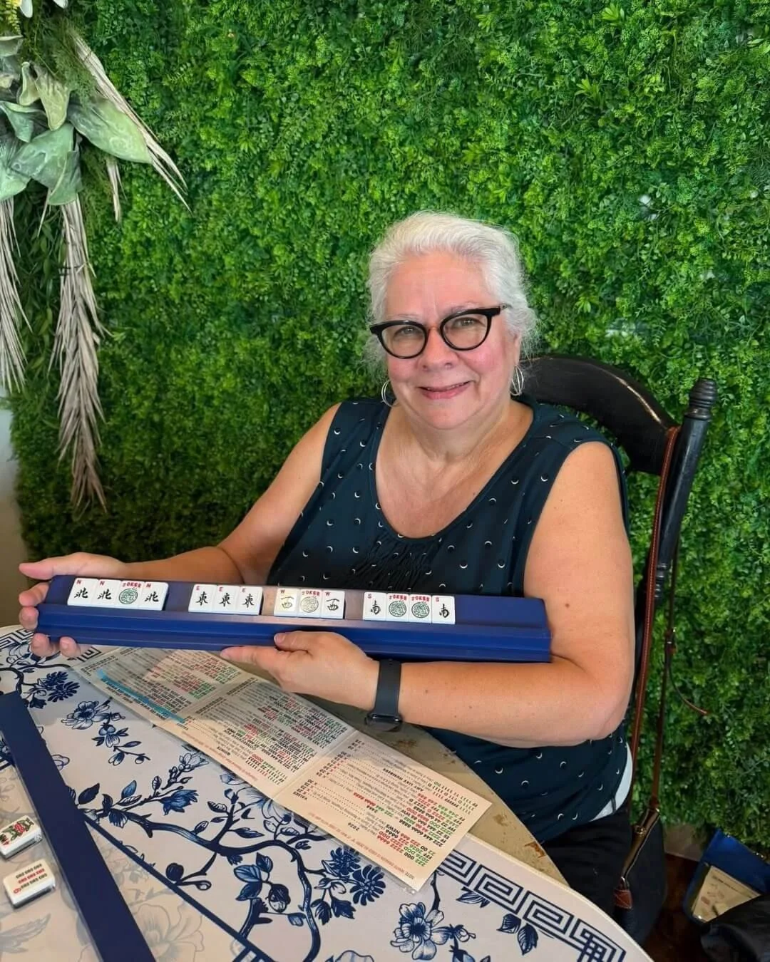 Happy woman in her 70s holding up her winning tiles for American Mahjong