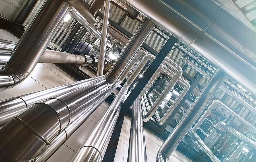Interior view of an industrial building or parking garage, featuring stainless steel pipes and metal structures.