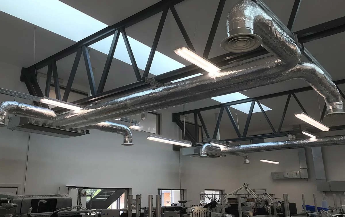 Industrial interior with exposed ductwork and structural beams in a modern workspace or factory.