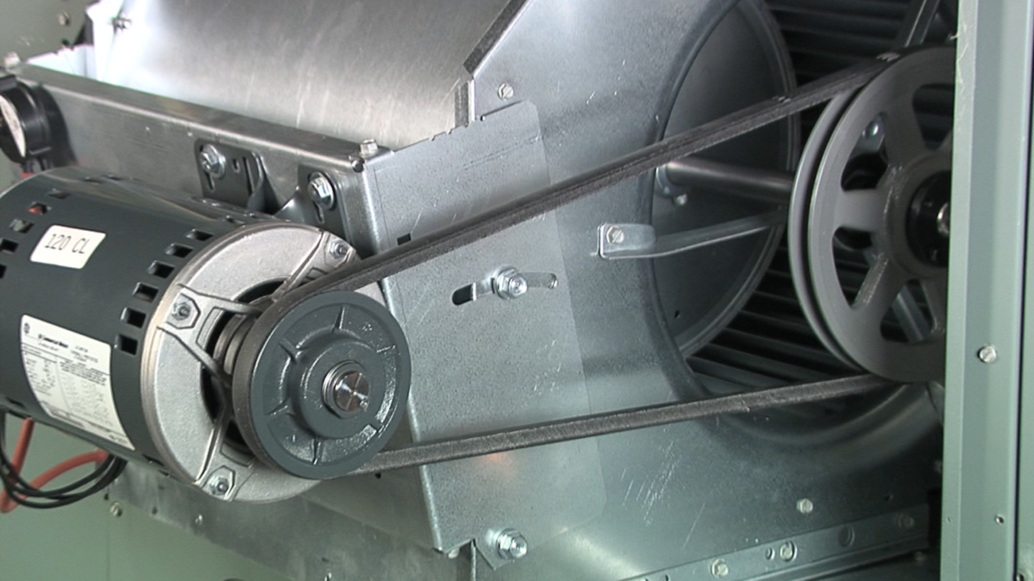 Close-up of mechanical parts including a motor, pulleys, and belts inside an industrial machine.