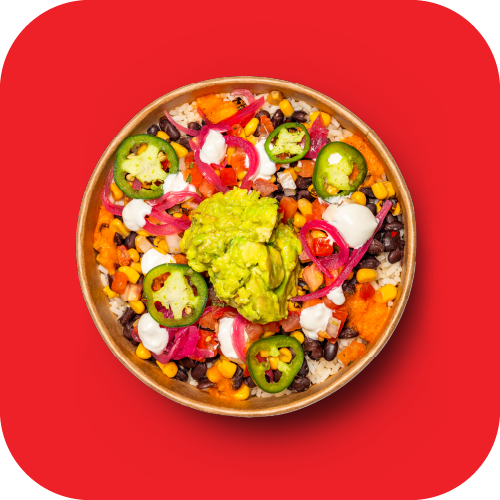 Bowl of Mexican-style rice and beans topped with guacamole, sliced jalapeños, sour cream, pickled onions, and corn, on a red background.