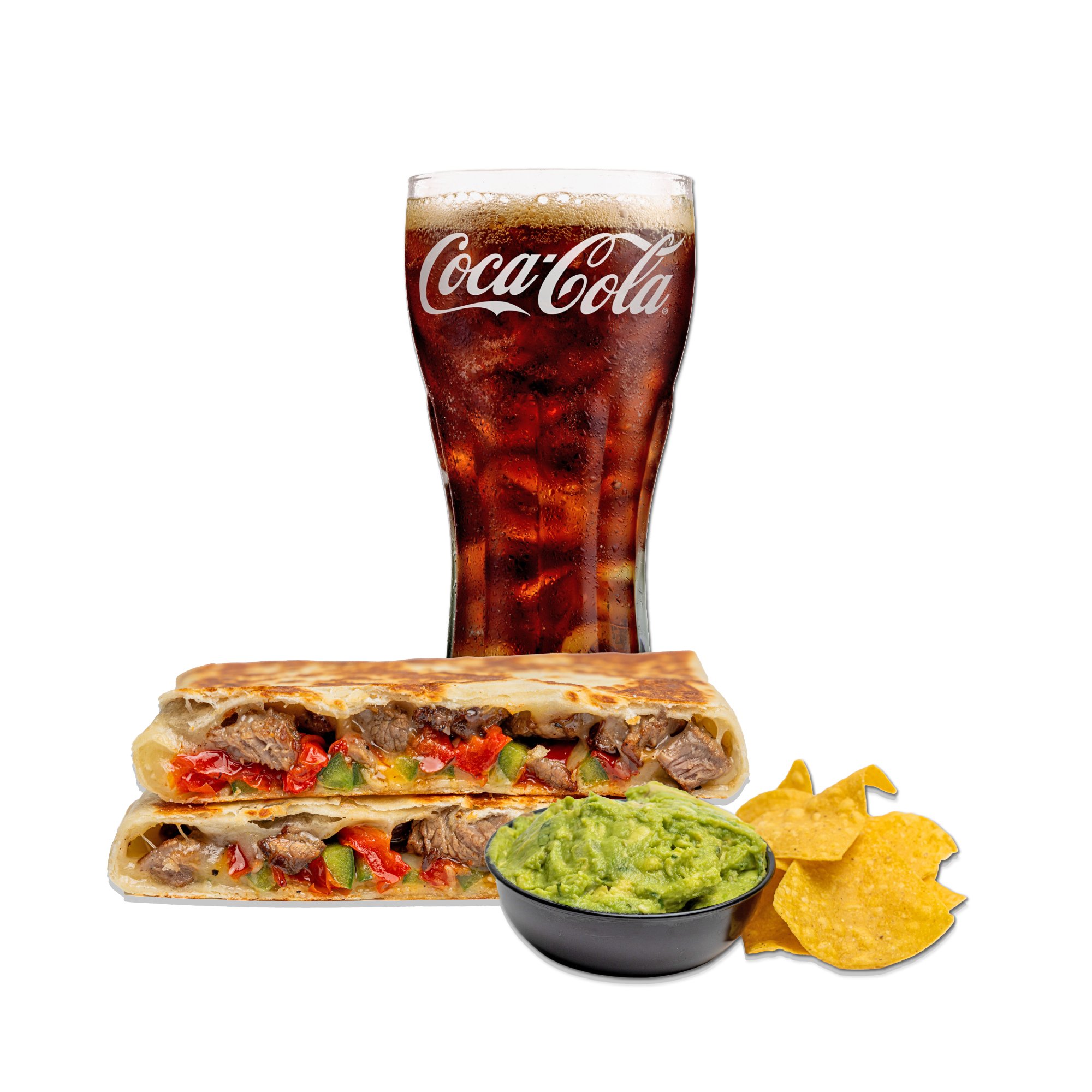 A Coca-Cola glass filled with soda and ice, a beef and SPICY STEAK quesadilla, a small bowl of guacamole, and a few tortilla chips.