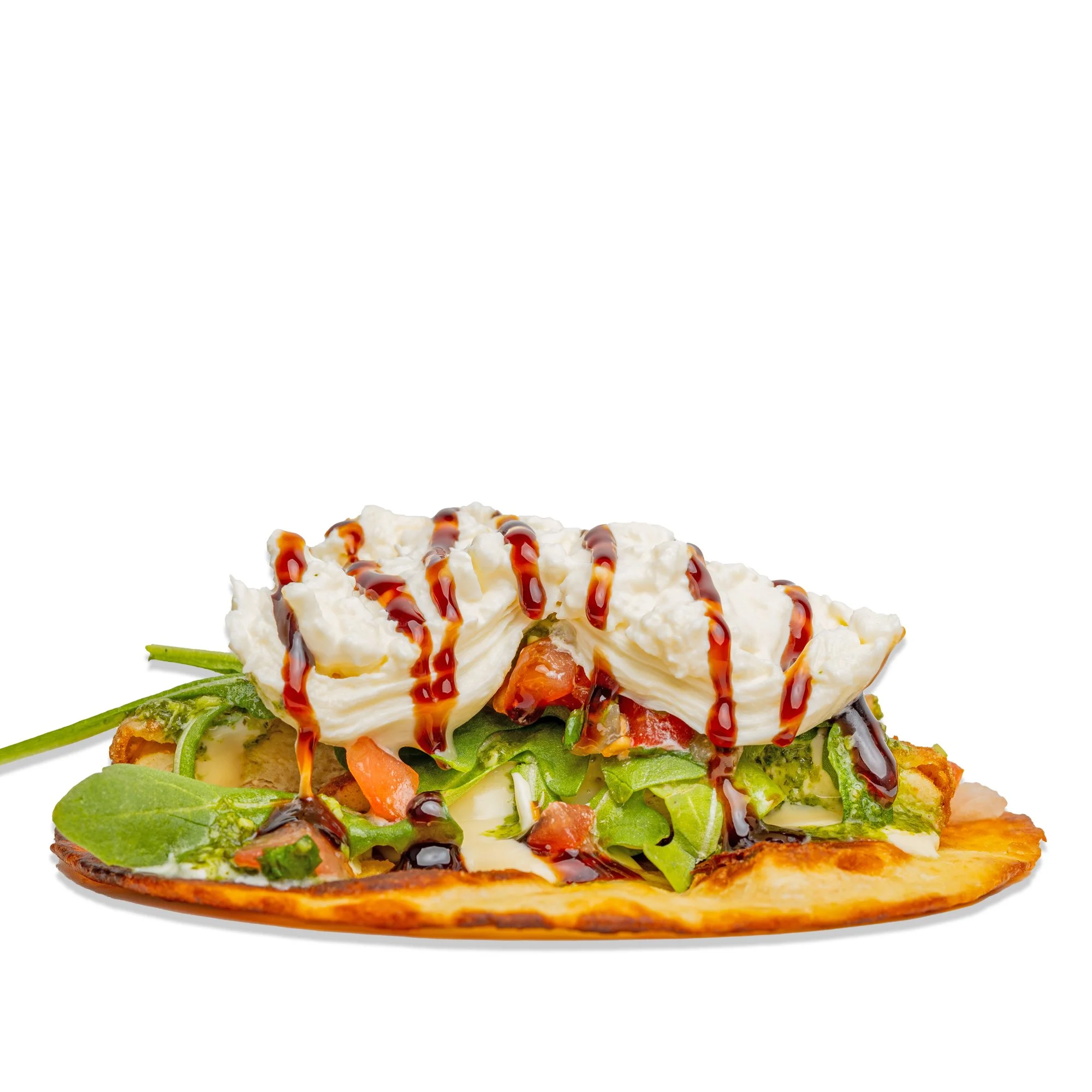 Flatbread topped with greens, chopped vegetables, dollops of sour cream, and drizzled with balsamic glaze.
