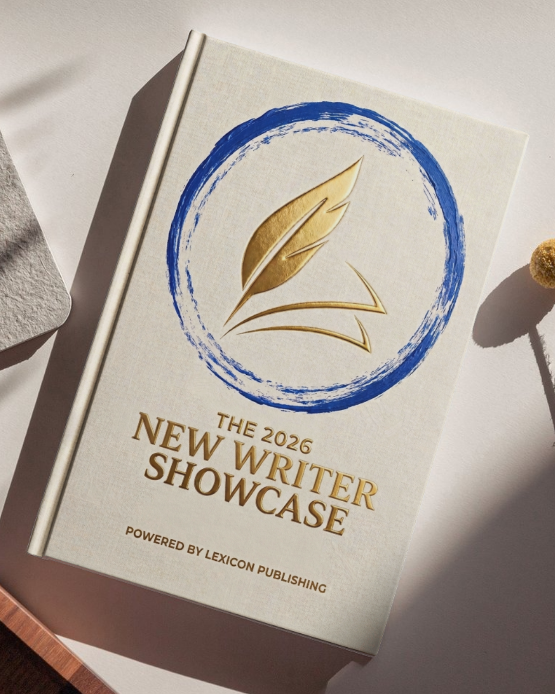 A brochure for the 2026 New Writer Showcase, powered by Lexicon Publishing, featuring a gold feather logo enclosed in a blue circular brushstroke on a white cover.