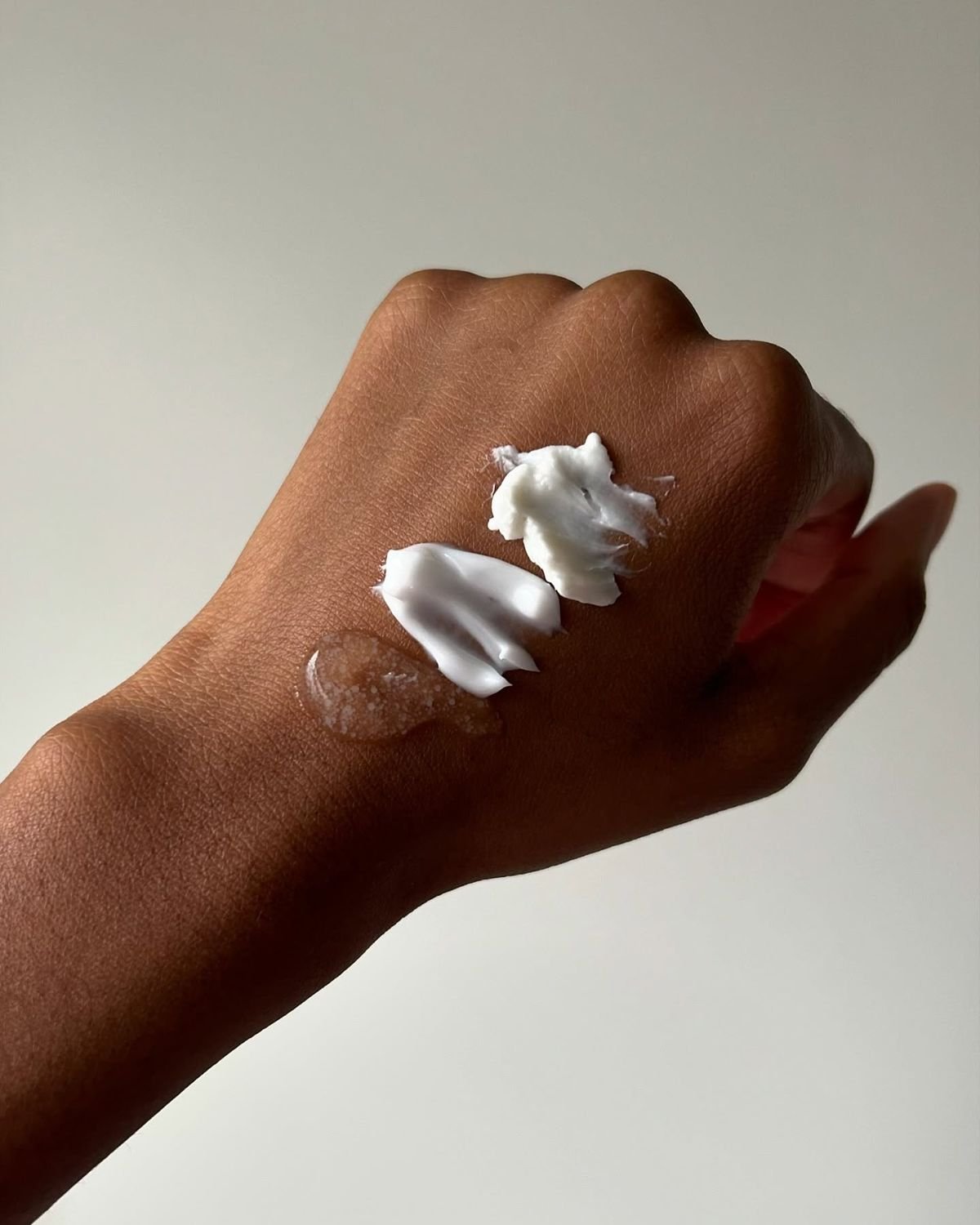 Mano con crema y loción blanca en los dedos