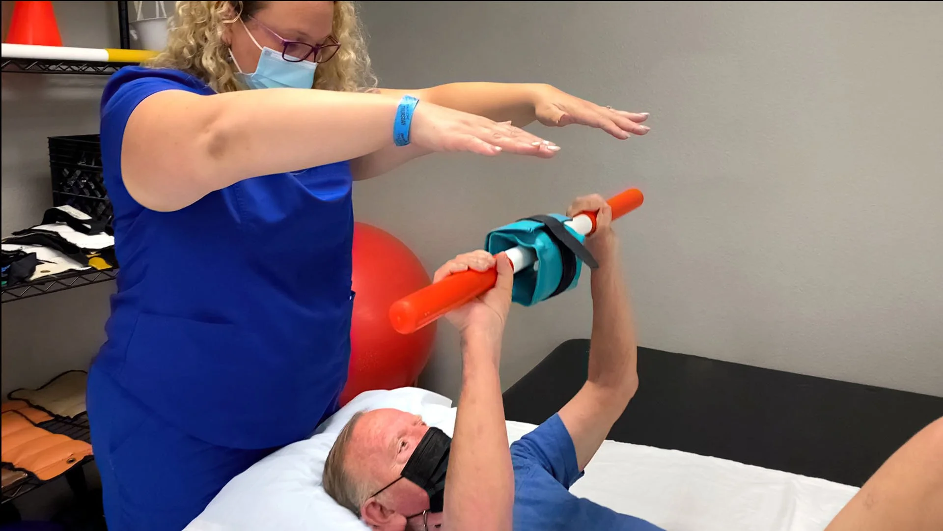 Therapist assisting patient with exercise using a resistance bar.