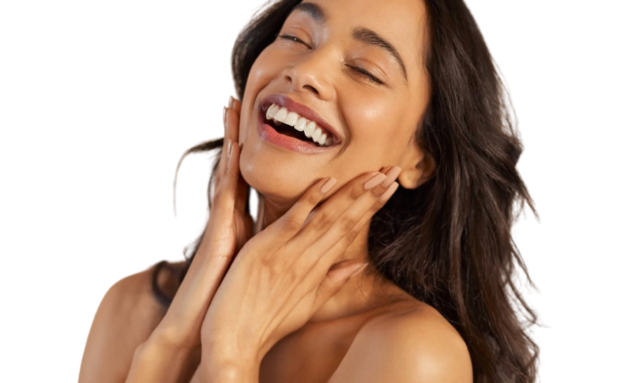 A woman with long brown hair laughing and touching her face with both hands, against a white background.
