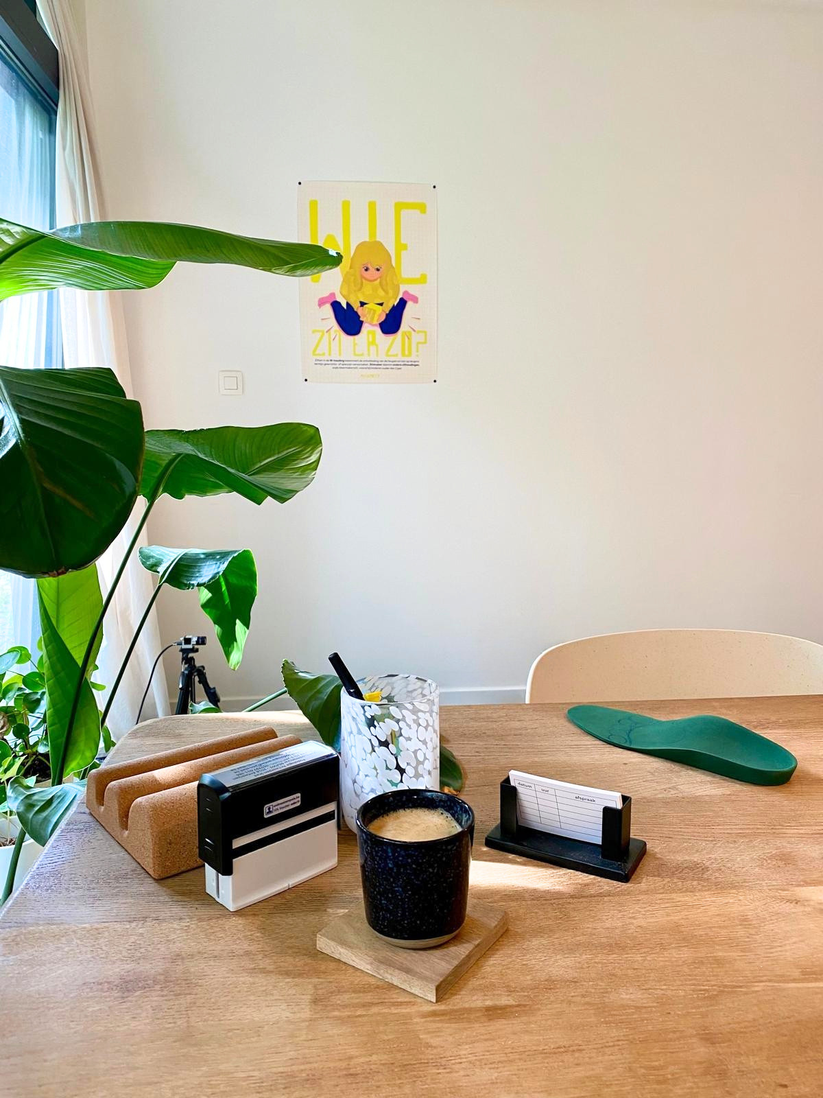 Een praktijkruimte van een podoloog met een poster met een cartoon van een meisje op de witte muur. De poster beeldt een kind af dat in de W-houding zit. De poster wijst op het belang van het vermijden van de W-zit en is informatief en kleurrijk.