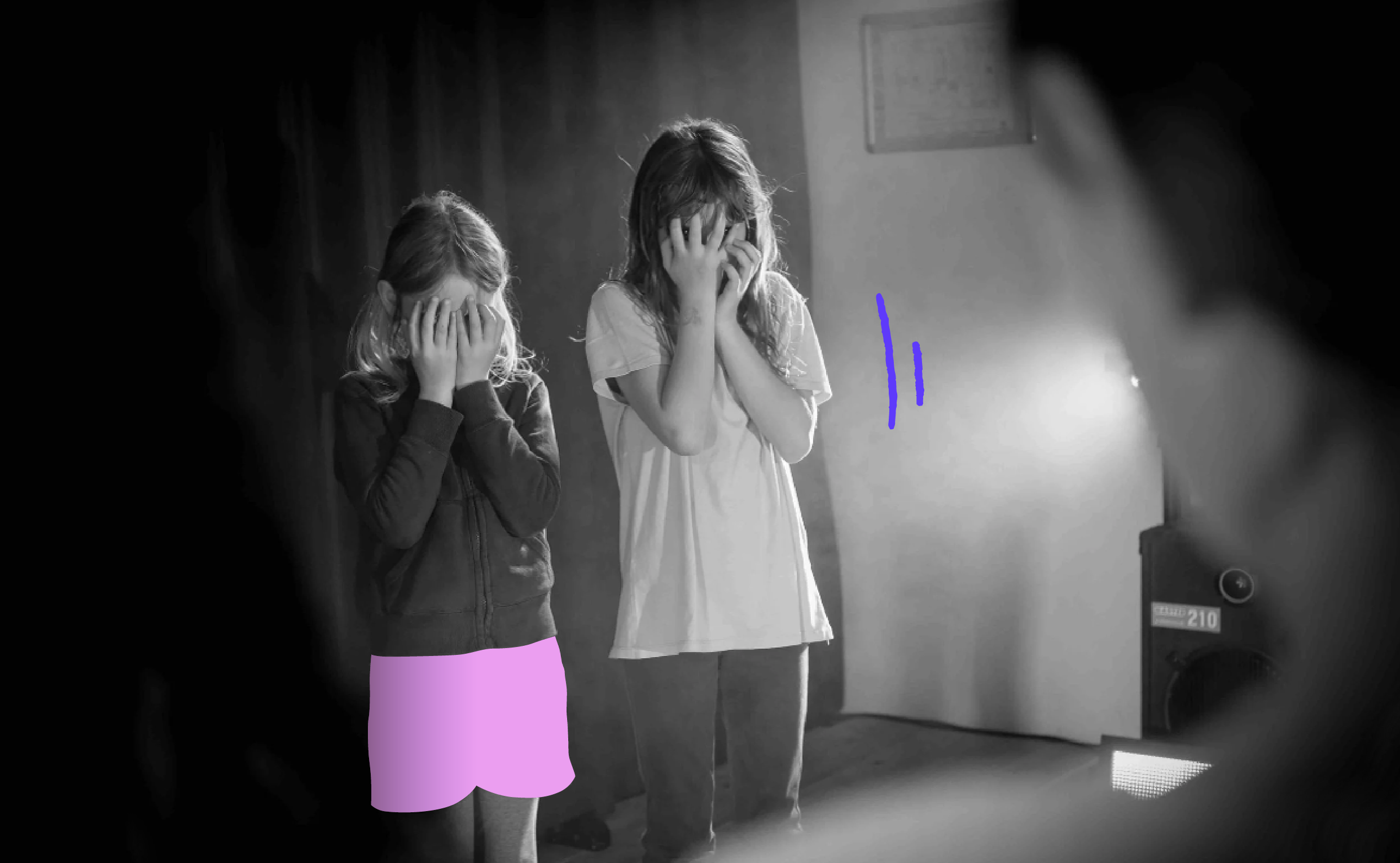 Deux jeunes filles, apparemment en détresse, se couvrent le visage avec les mains dans une scène en noir et blanc, probablement une reconstitution ou une performance artistique.