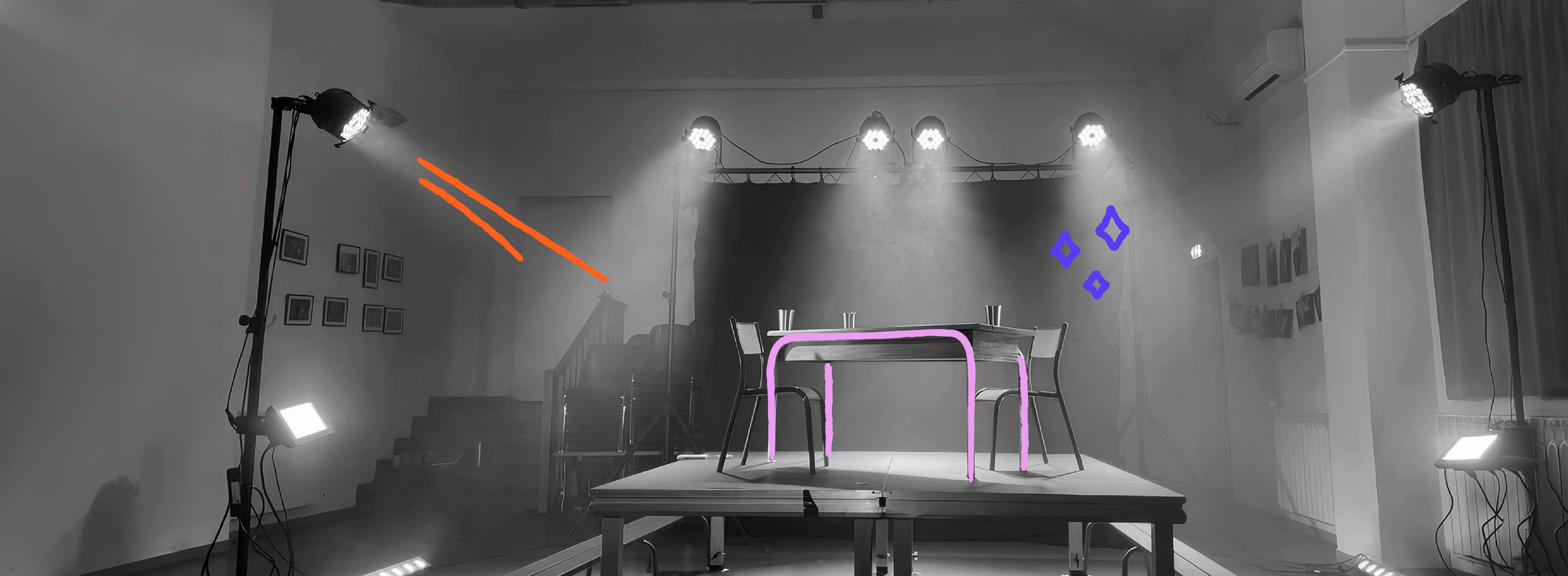 Une scène en noir et blanc d'une salle avec un petit plateau surélevé, entouré de lumière de scène. Sur le plateau, il y a une table en bois avec deux chaises, une à chaque extrémité. Des éléments en couleur, notamment des lignes orange, des formes bleues, et des contours violets, ont été dessinés sur l'image.