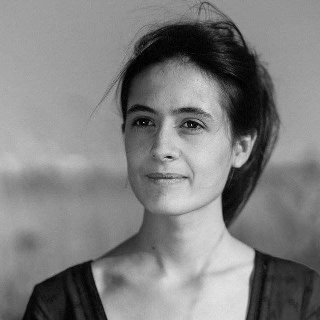 Portrait d'une femme souriante regardant au loin dans un paysage naturel.