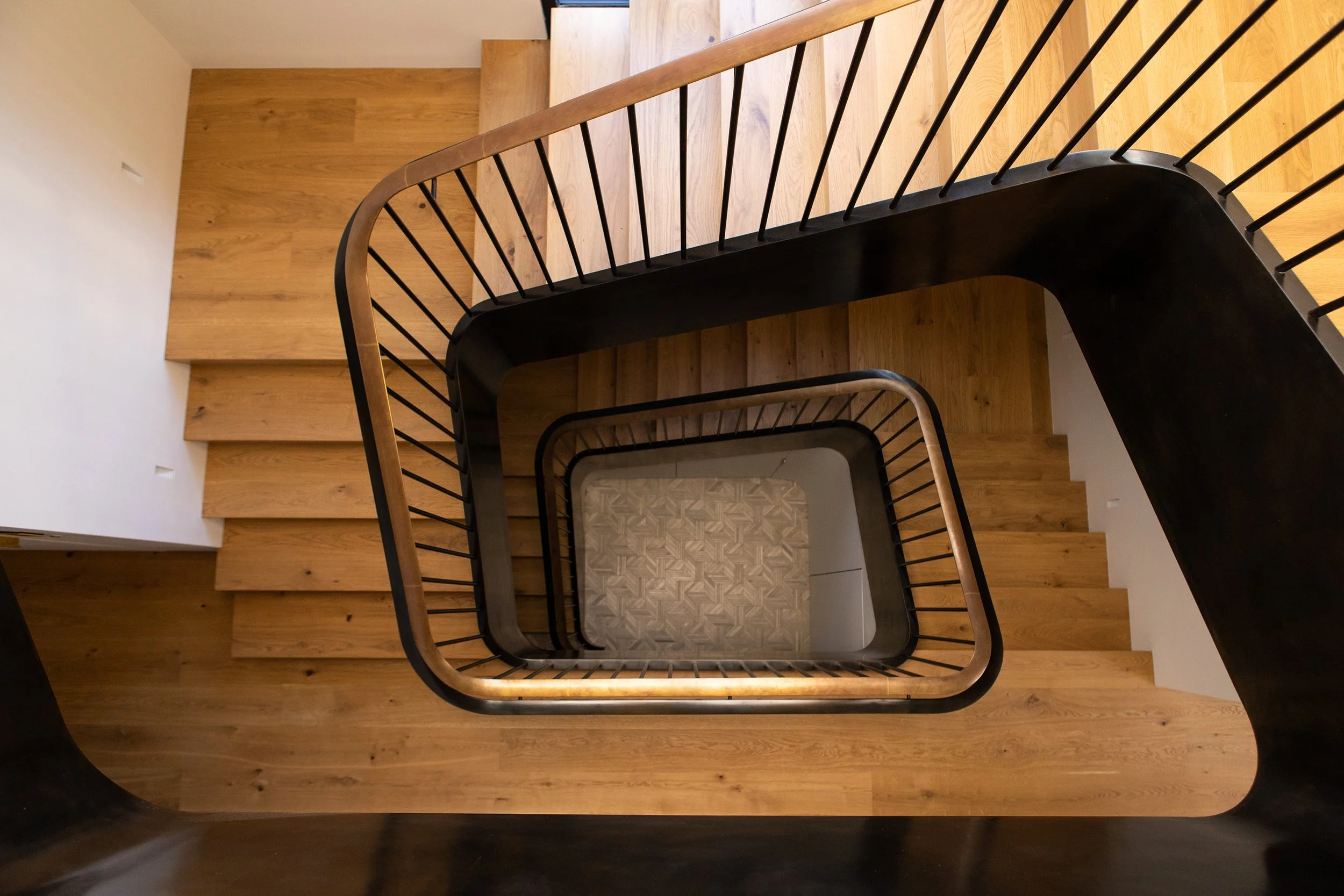 Top view of a staircase with wooden steps and black metal railing, looking from above.
