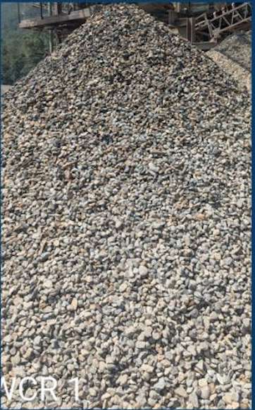 A large pile of small gray and white gravel stones outdoors near a building.
