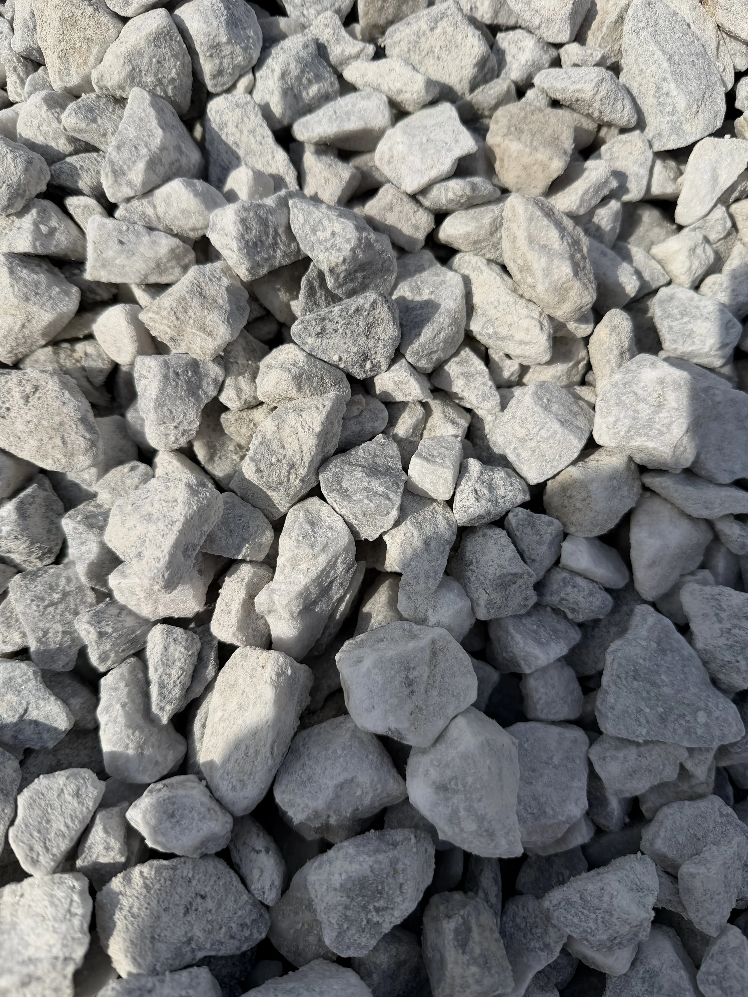 A close-up image of small, irregularly shaped gray and white rocks or gravel pile.