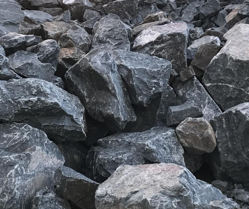 A pile of large, irregularly shaped gray rocks with some white veins or streaks.