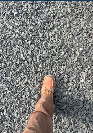 Person walking on gravel path, wearing tan pants and brown hiking boots.
