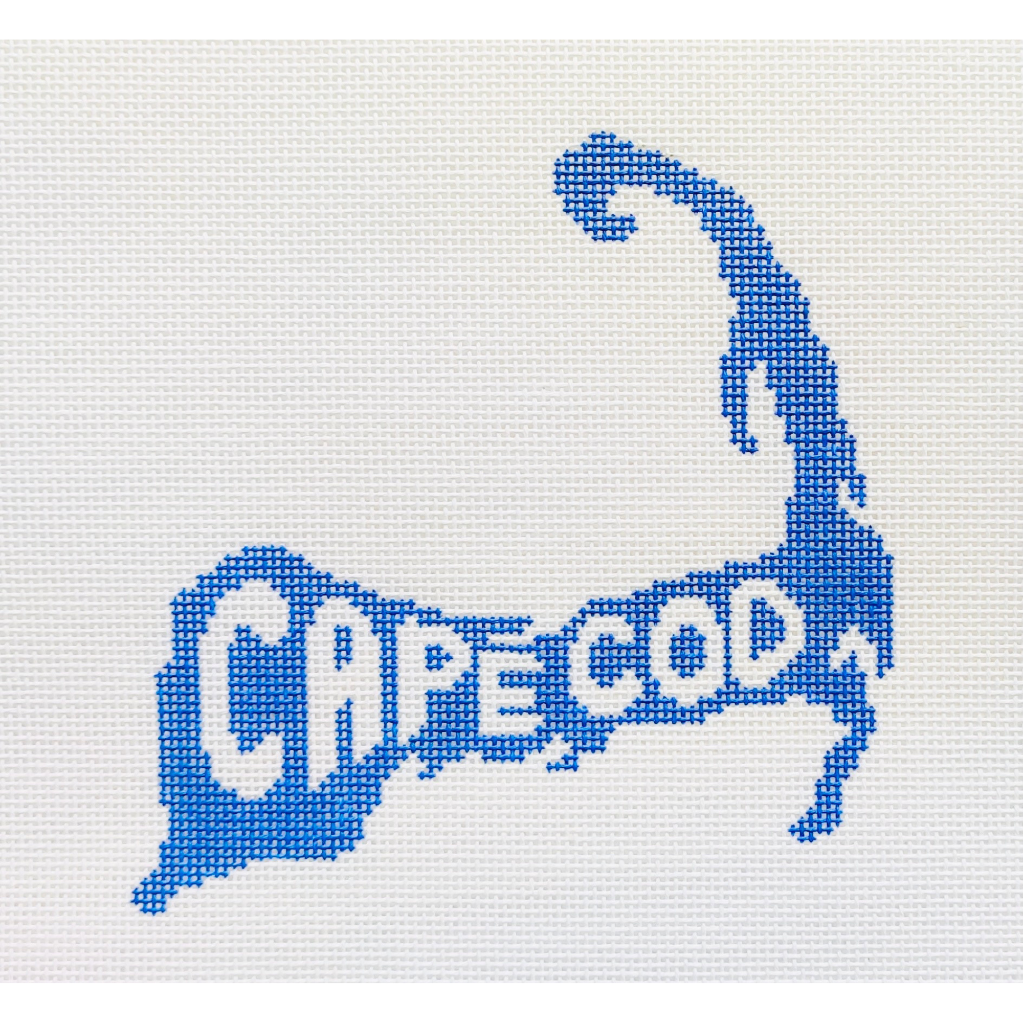 Needlepoint design of the outline of Cape Cod with the word "CAPE COD" inside it on a white fabric background.