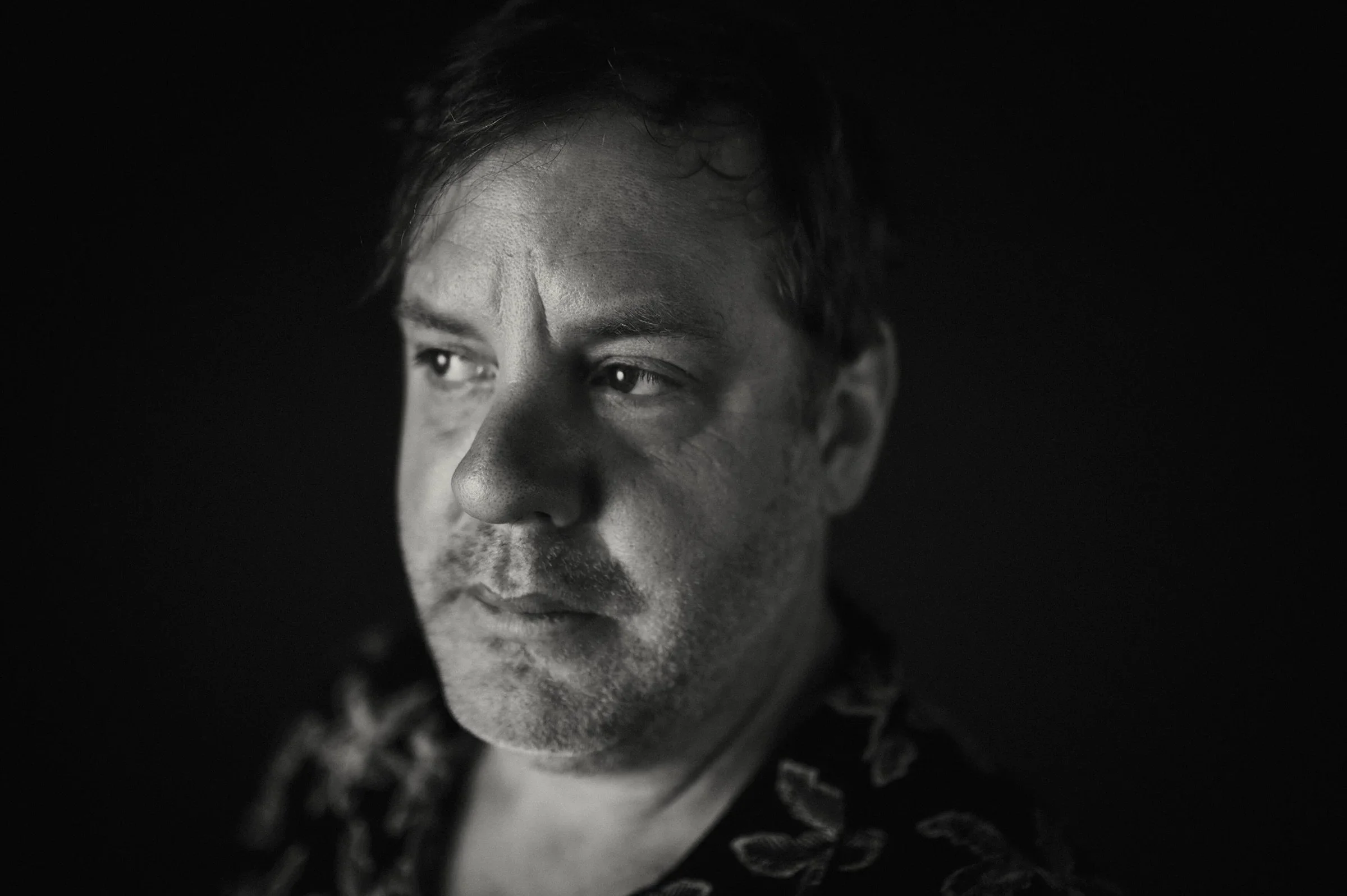 Black and white portrait of a man looking to the side with a serious expression.