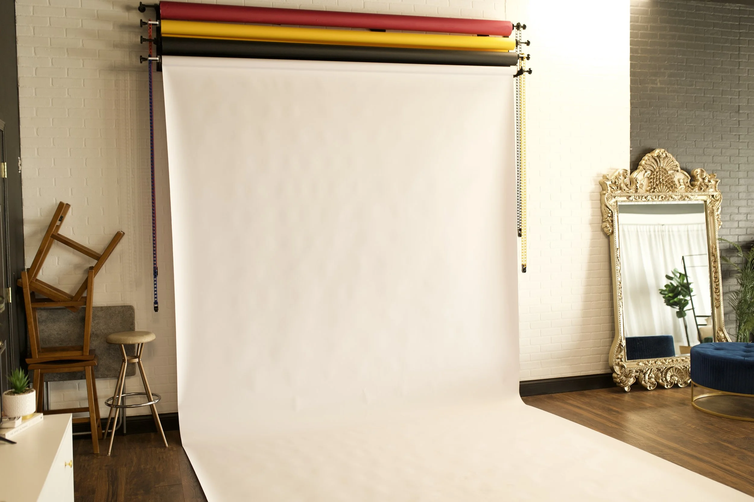 Photography backdrop with white roll paper and colored rolls at the top, in a stylish room.