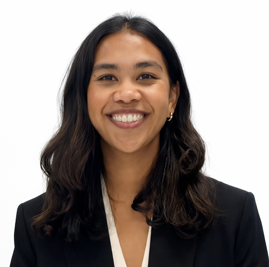 Close-up of a smiling woman with wavy dark hair wearing a black blazer and a white top, against a white background.