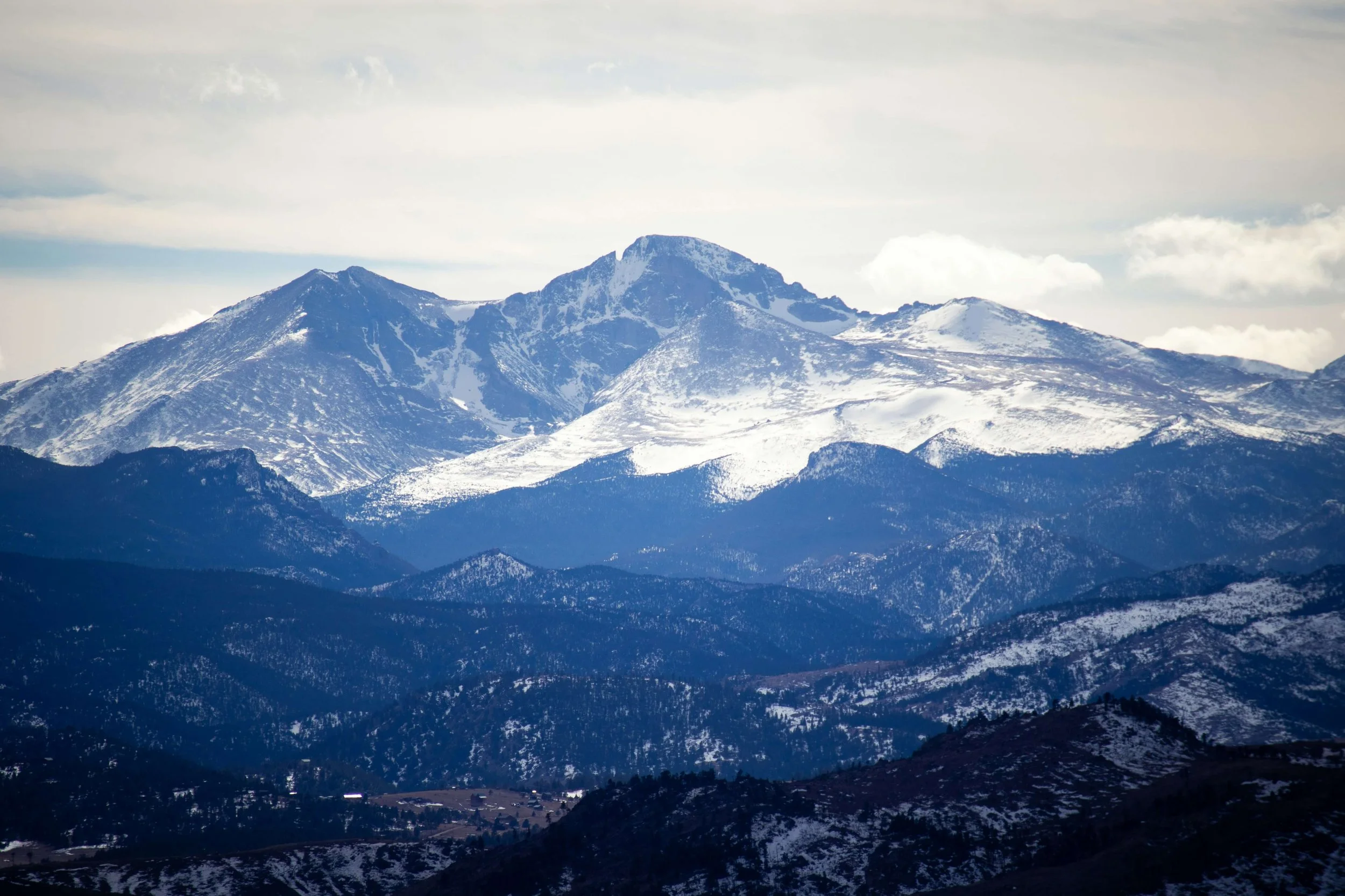 Snow-capped mountain range under a cloudy sky.