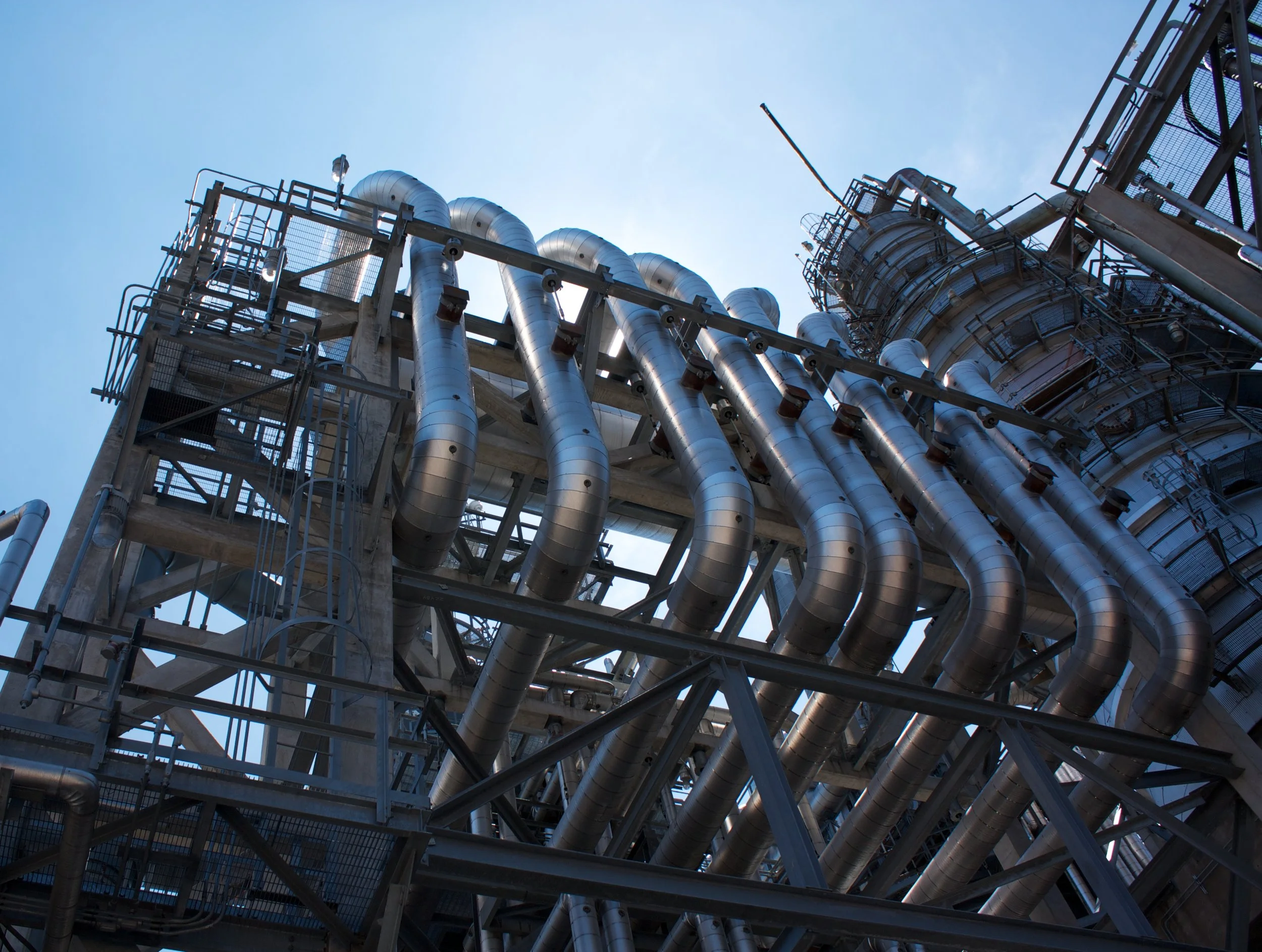 Industrial facility with metal pipes and structures against a blue sky.