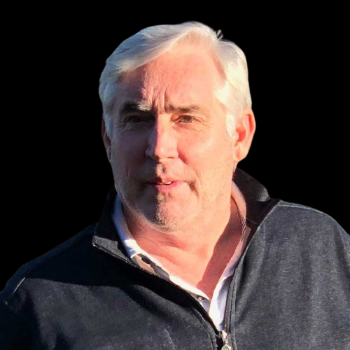 Portrait of a man with white hair and a black jacket against a black background.