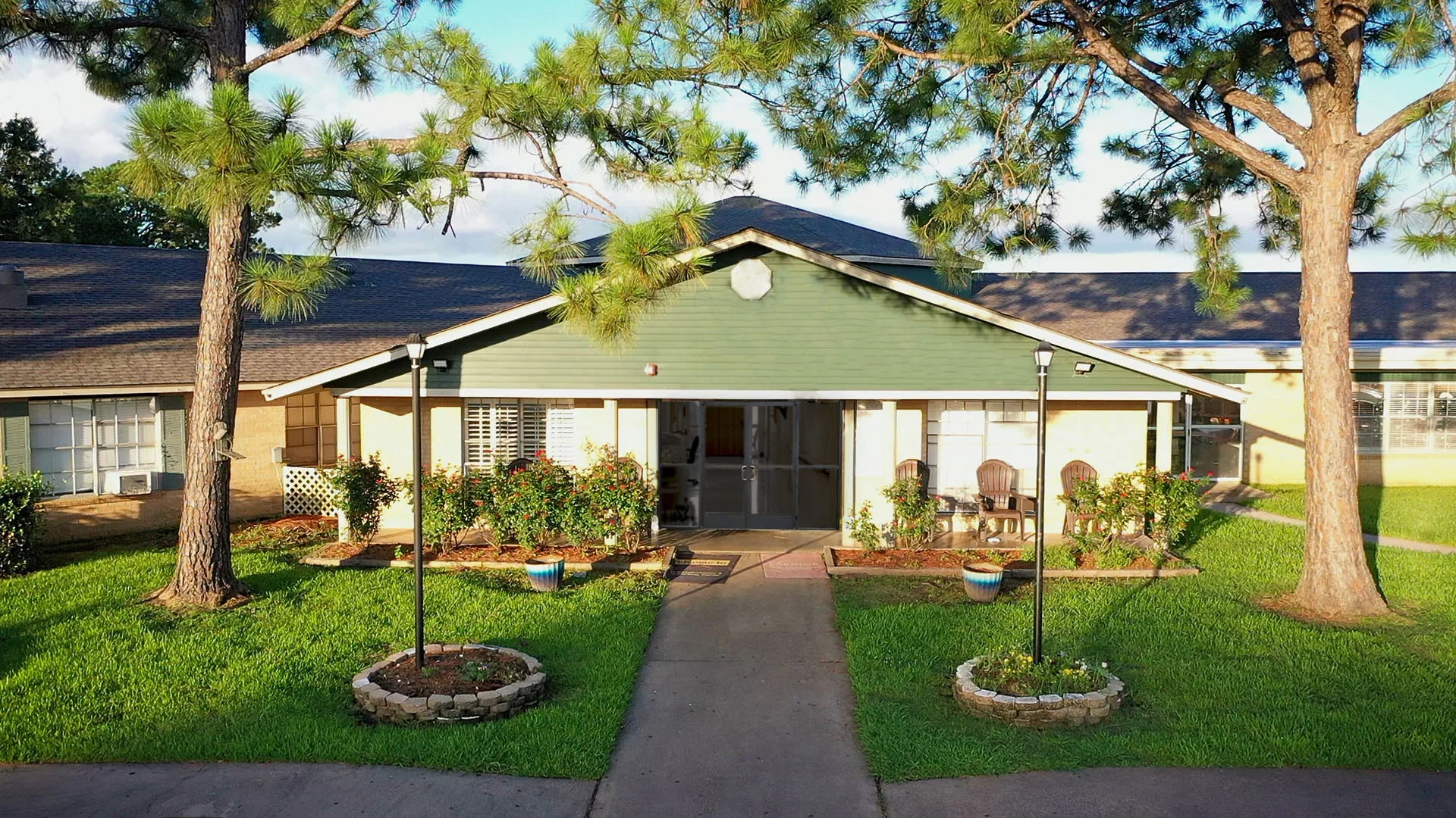 Single-story green house with porch and pathway.