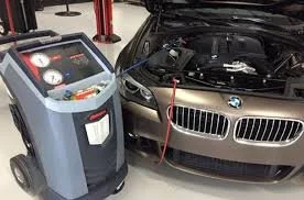 A BMW car connected to a portable air conditioning or cooling machine with hoses, inside a garage