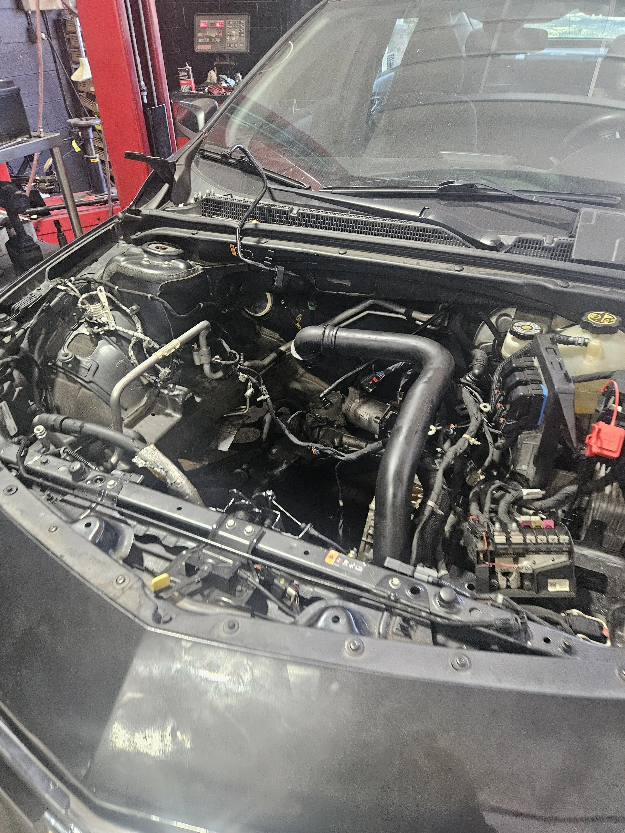 Car engine being worked on in a garage or repair shop with tools and equipment nearby.