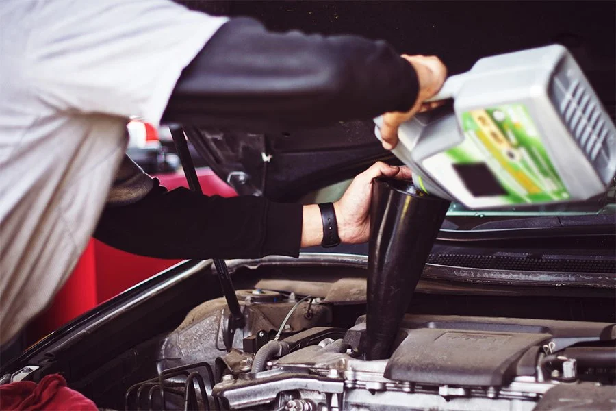Person pouring windshield washer fluid into a car engine