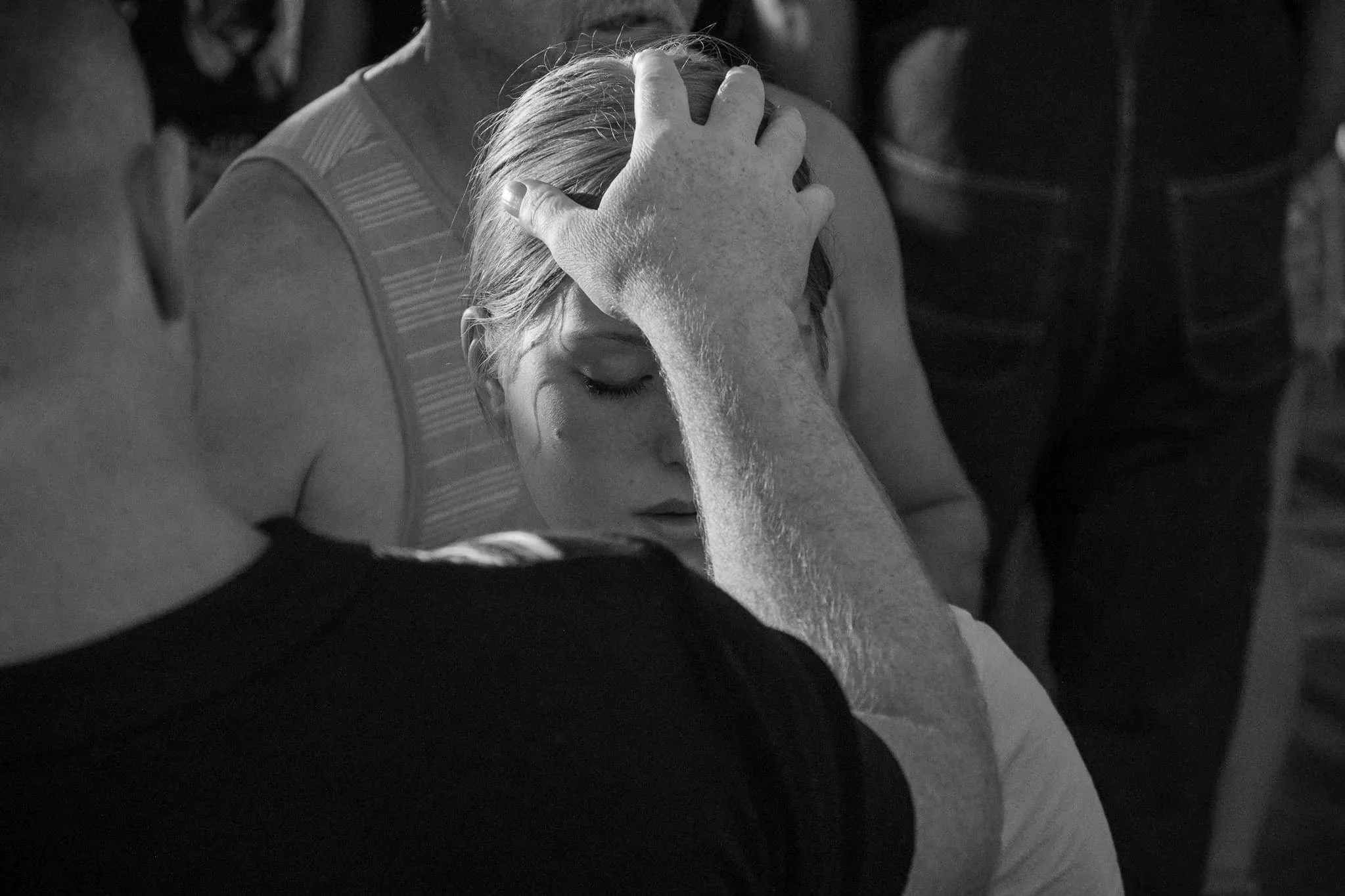 Close-up of a person with light-colored hair holding their head with their hand, appearing distressed, in a black-and-white photo.