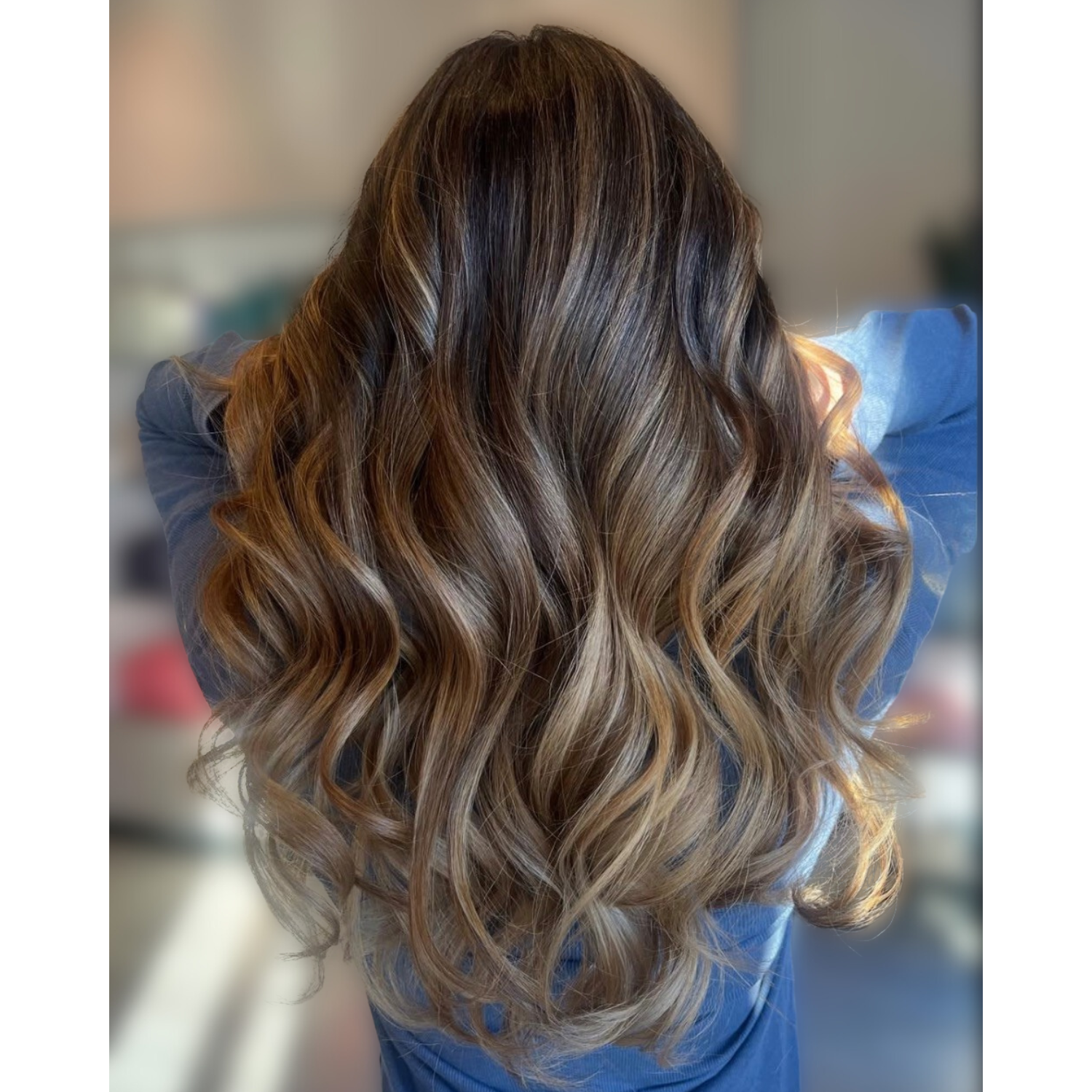 Back view of a woman with long, wavy, caramel-colored hair.
