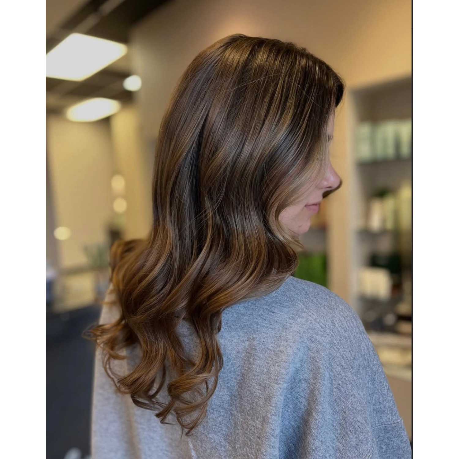Side view of a woman with medium-length, wavy brown hair.