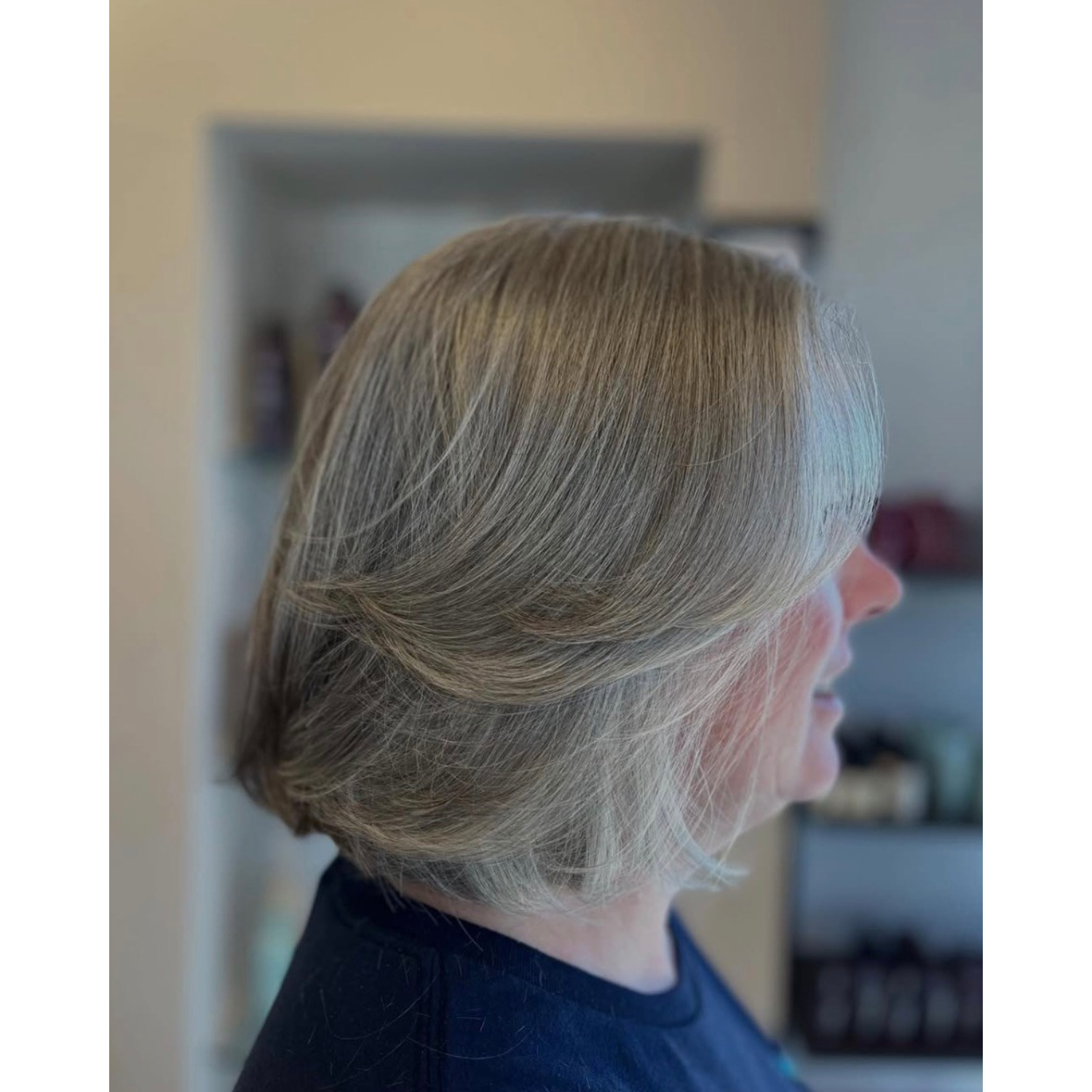 Side view of a woman with short, flowing gray hair styled neatly.