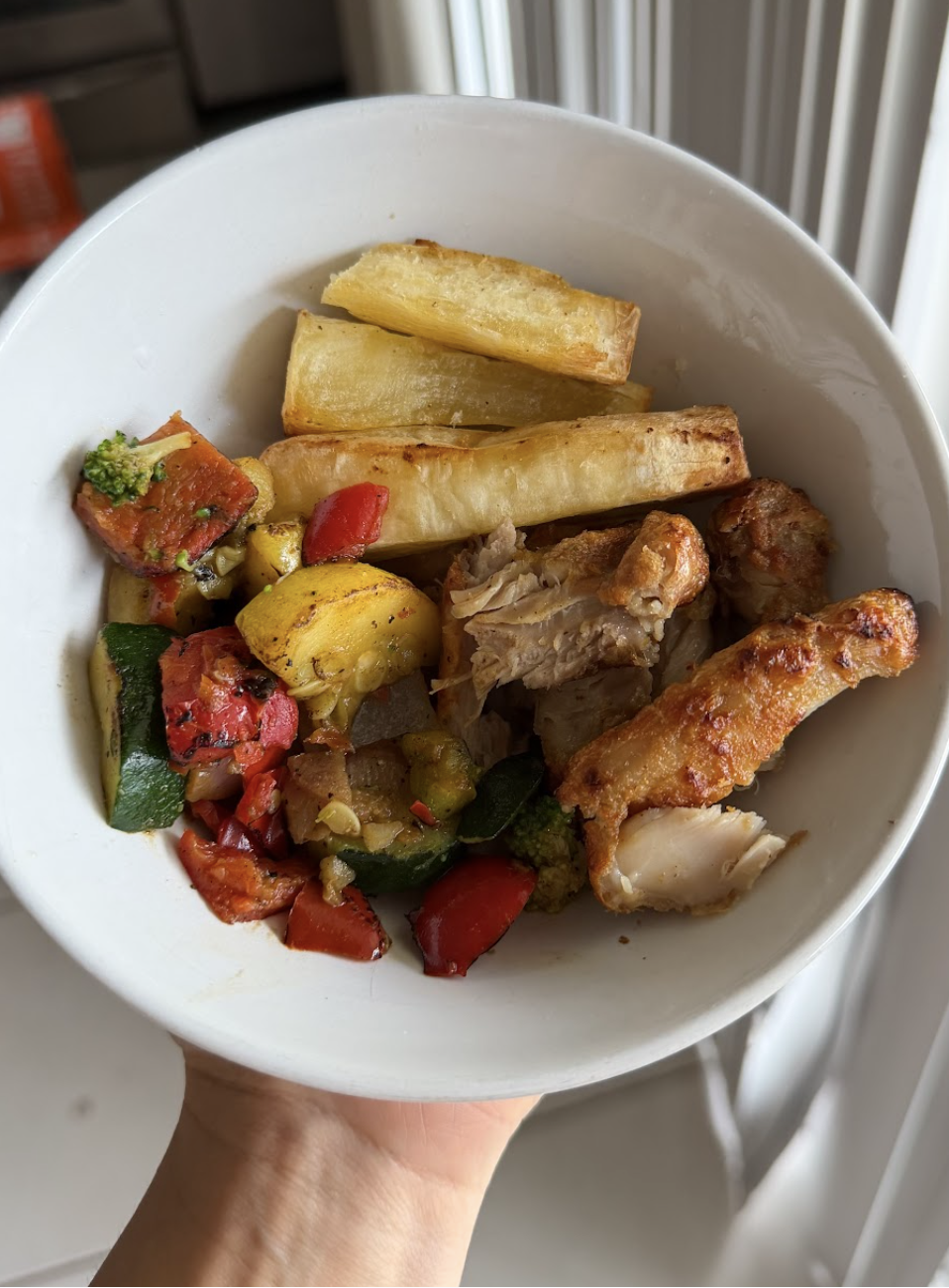 Plato de comida que incluye papas fritas, pollo frito, y vegetales asados o salteados como pimientos y calabaza.