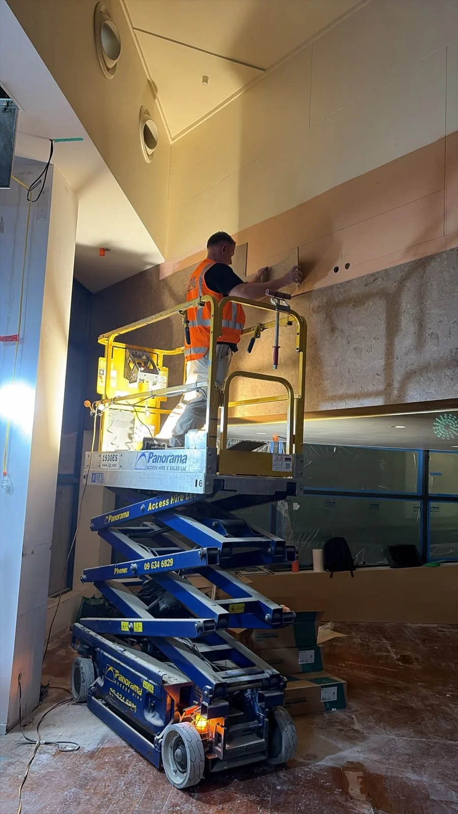 Form & Finish crew installing cork wall tiling at Sports & Rec Bar using scissor lift access.