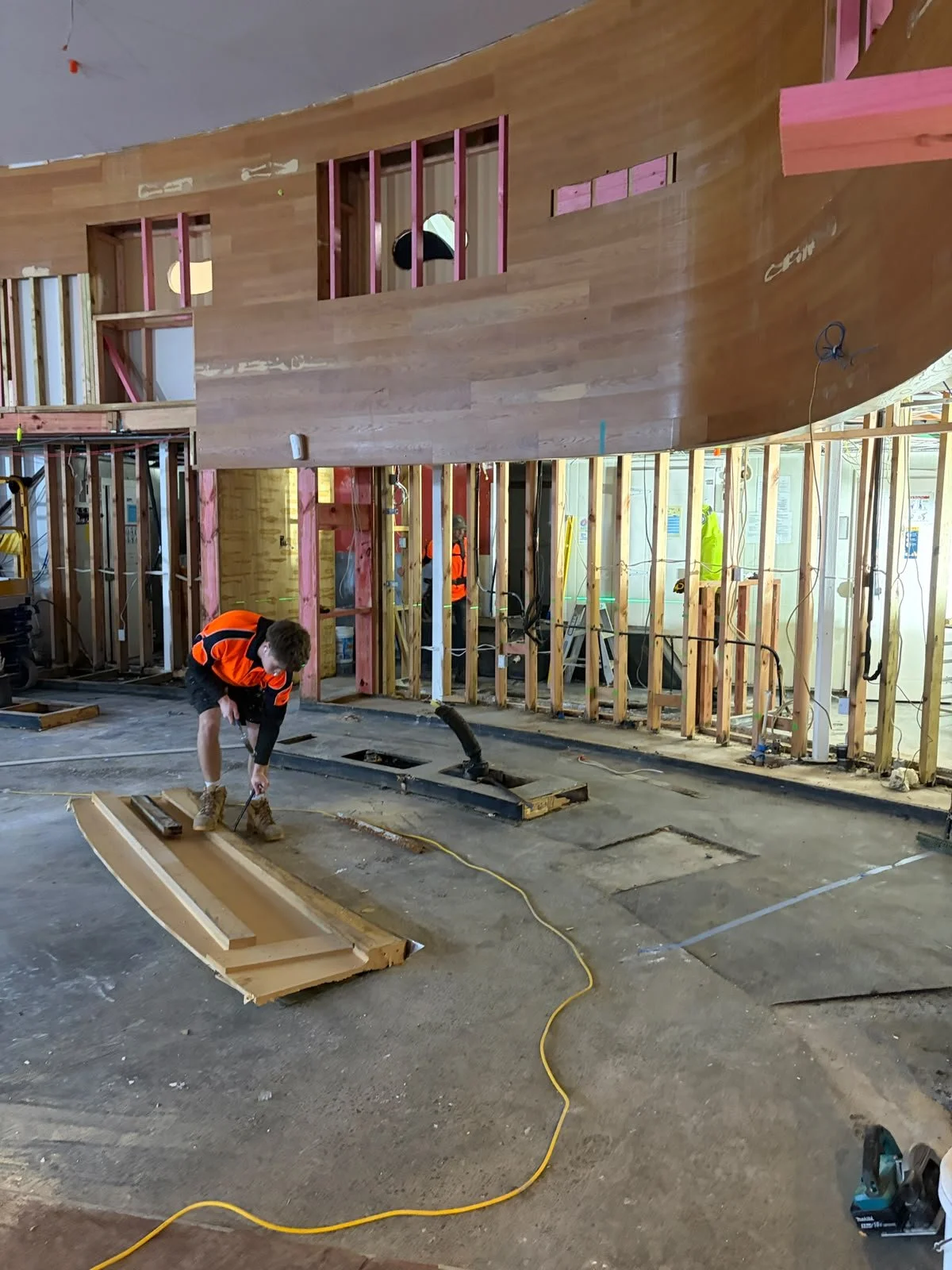 Curved timber wall panelling being installed at Sports & Rec Bar, with framing and joinery works in progress.