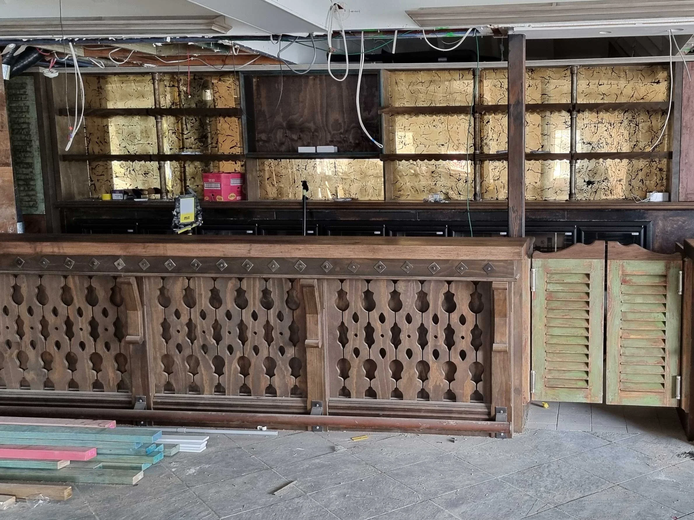Undergoing construction or renovation, with exposed wiring, partially installed wooden panels, and construction materials on the floor.