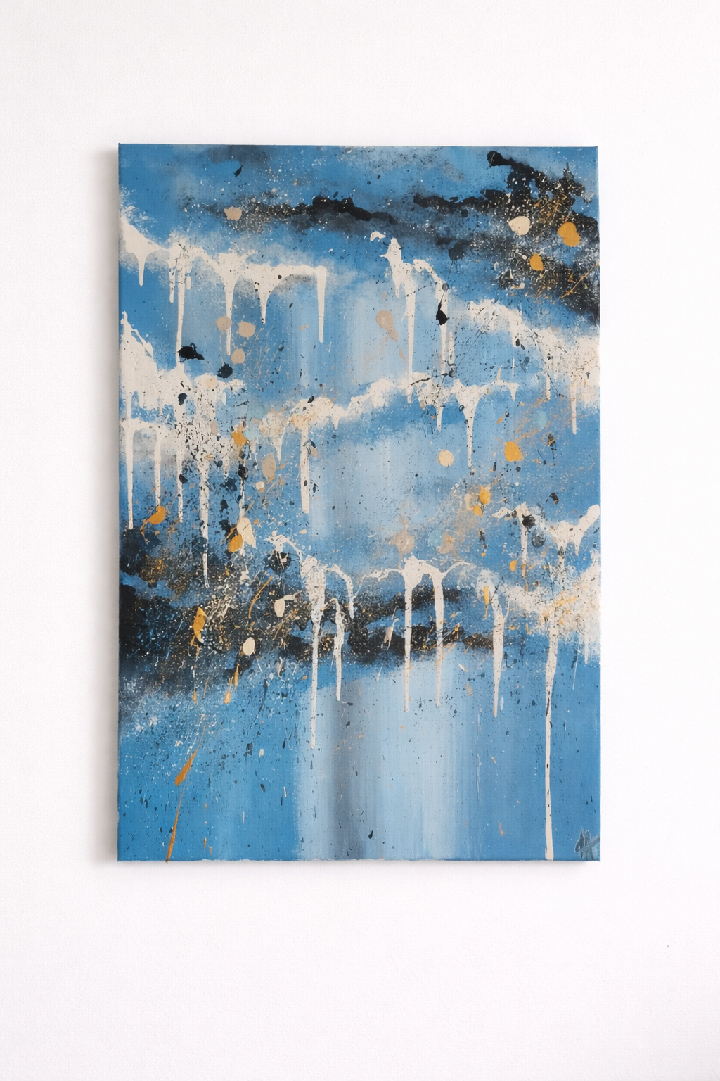 Abstract painting with blue, white, black, and gold splatters and drips on a canvas.