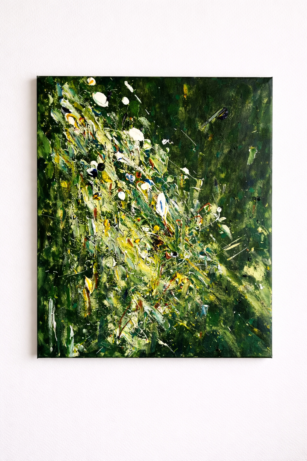 Abstract painting with green, white, yellow, blue, and red paint splatters and strokes on a canvas mounted on a white wall.
