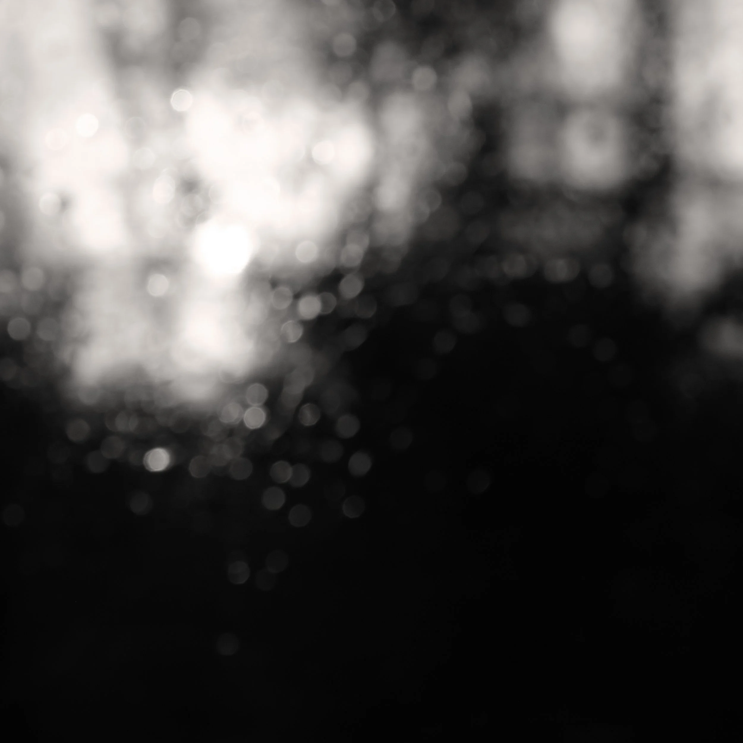 Blurred black and white photo of water droplets with light reflections.