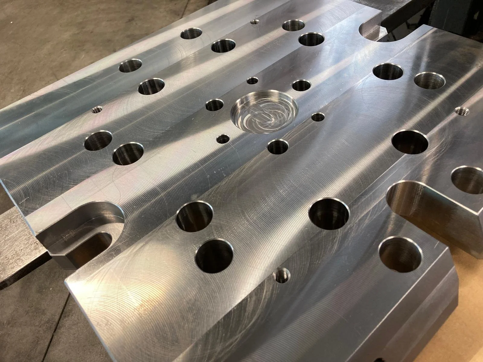 Una componente metallica di grandi dimensioni con numerosi fori e scanalature, probabilmente parte di un macchinario industriale.