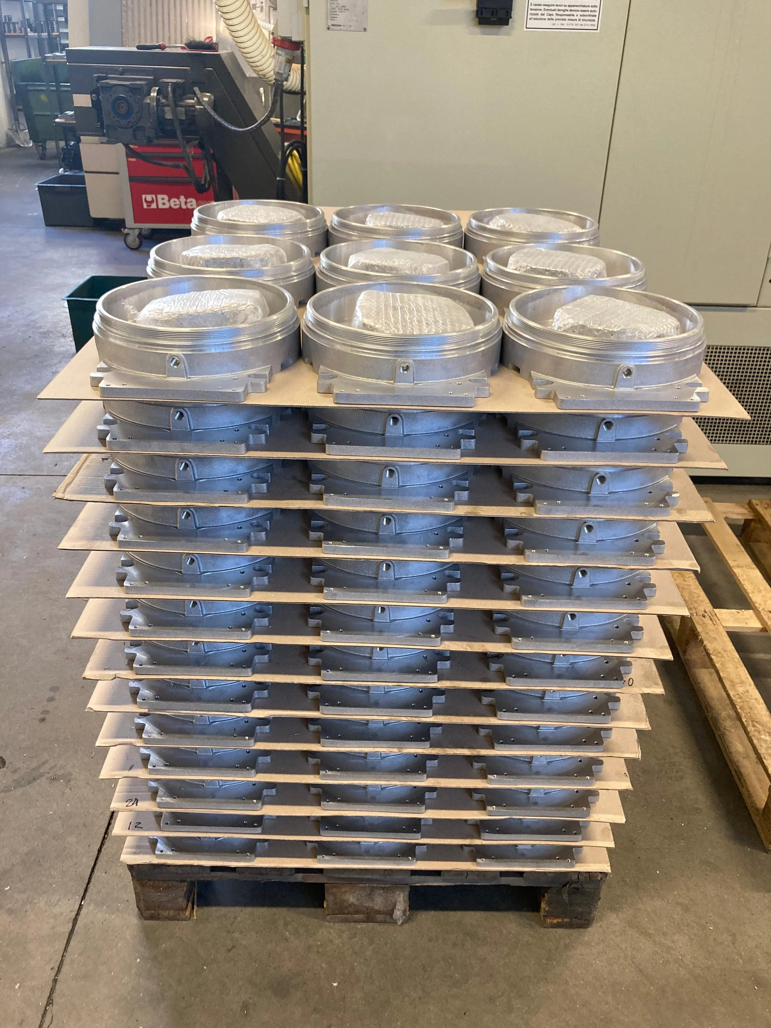 Lotto di componenti metallici impilati su un pallet in un ambiente industriale