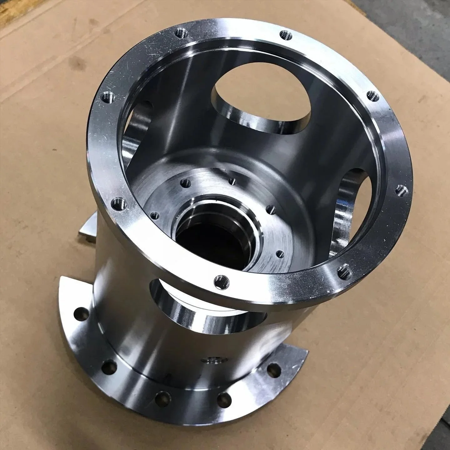 Componente metallico cilindrico con fori e superfici lucide, probabilmente parte di un'apparecchiatura industriale o meccanica.