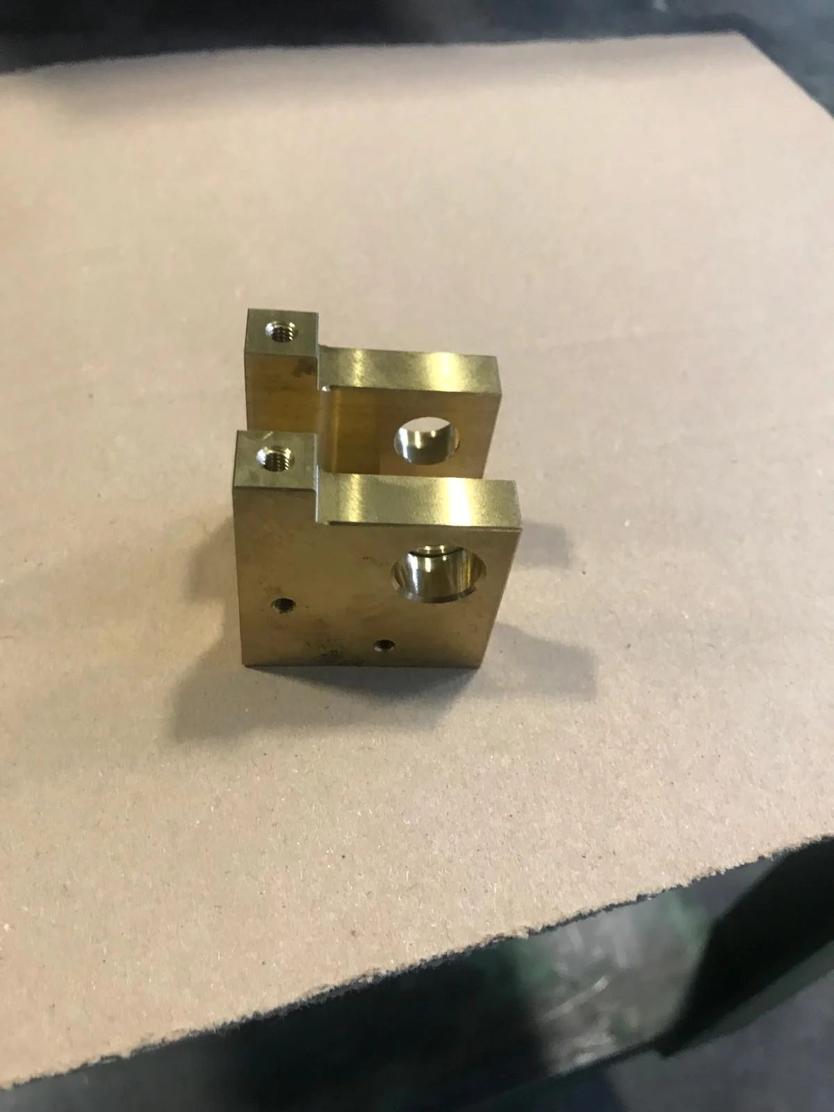 Mazzo di metallo con fori di precisione, probabilmente un componente meccanico, posto su una superficie di Schiuma